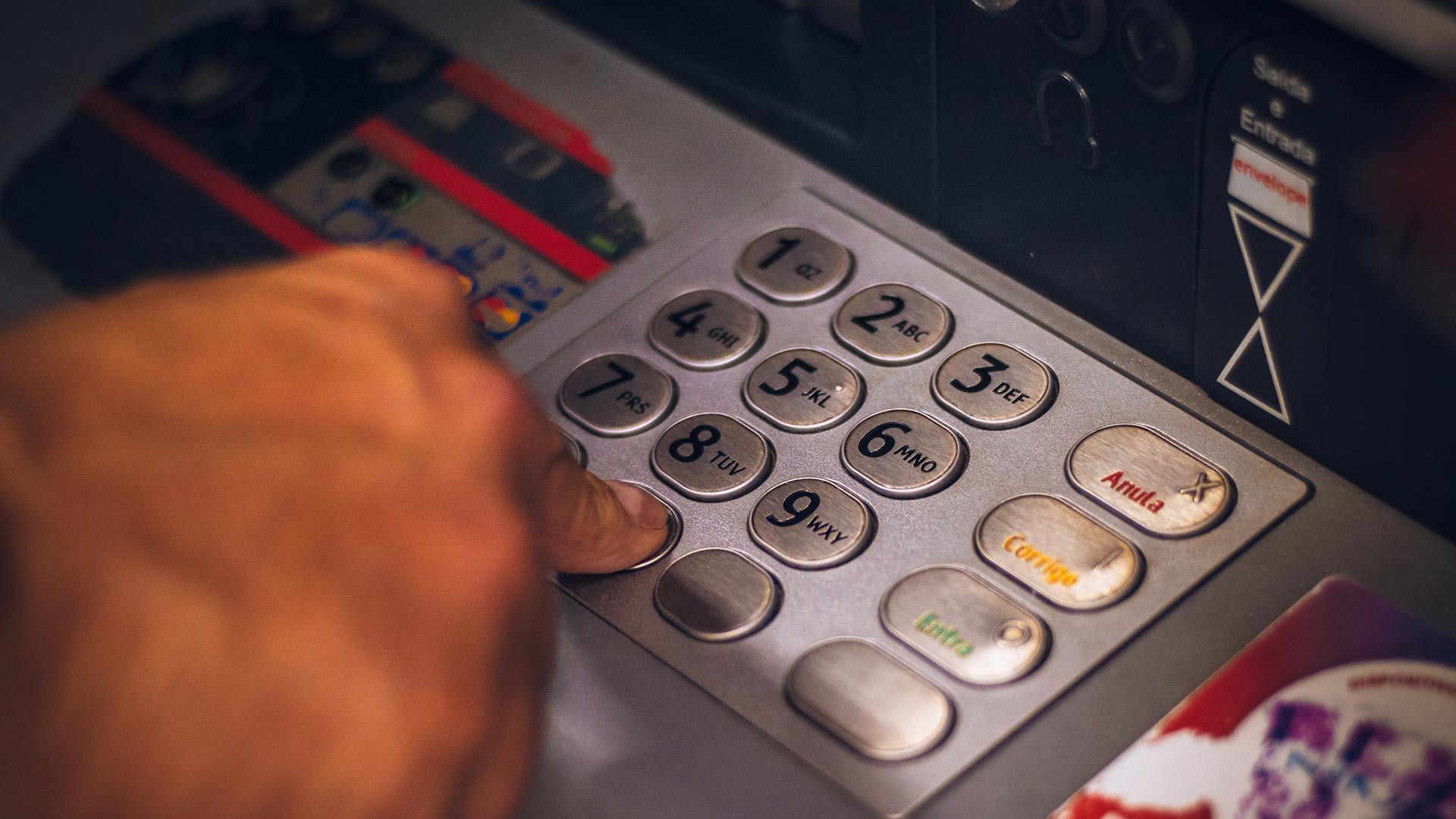 Una mano introduce su clave en un teclado numérico de un cajero automático